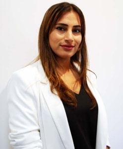 Zaina Sammour from Thomson & Associates - woman with long brown hair wearing a white jacket over a black v-necked shirt
